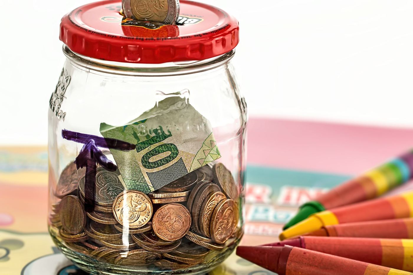 A glass jar filled with saved coins and banknotes